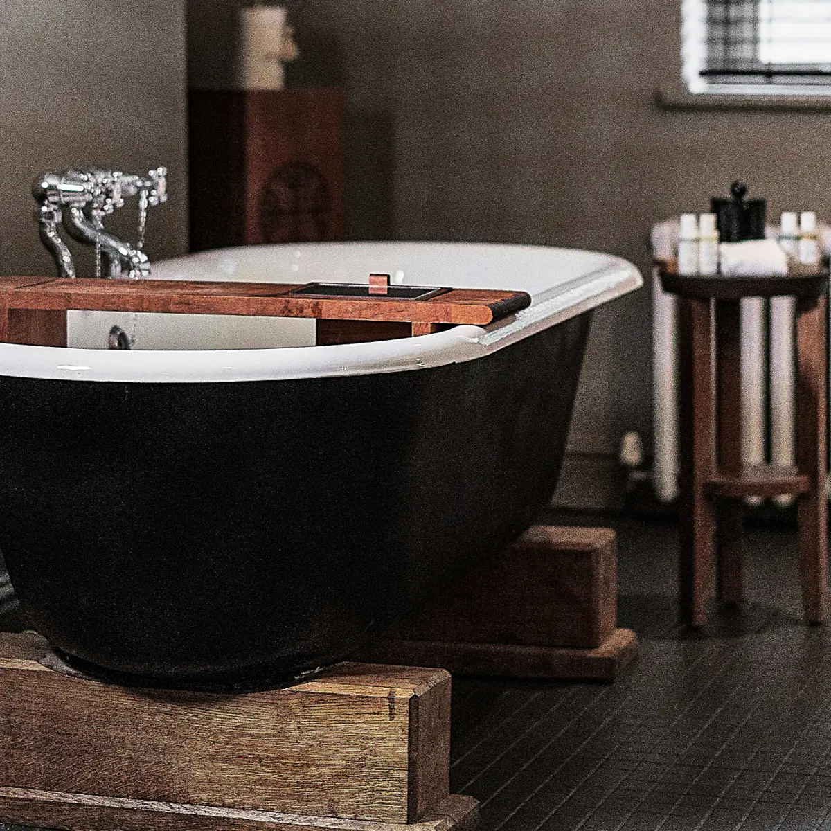 Black bathtub and wooden stand in a bathroom.