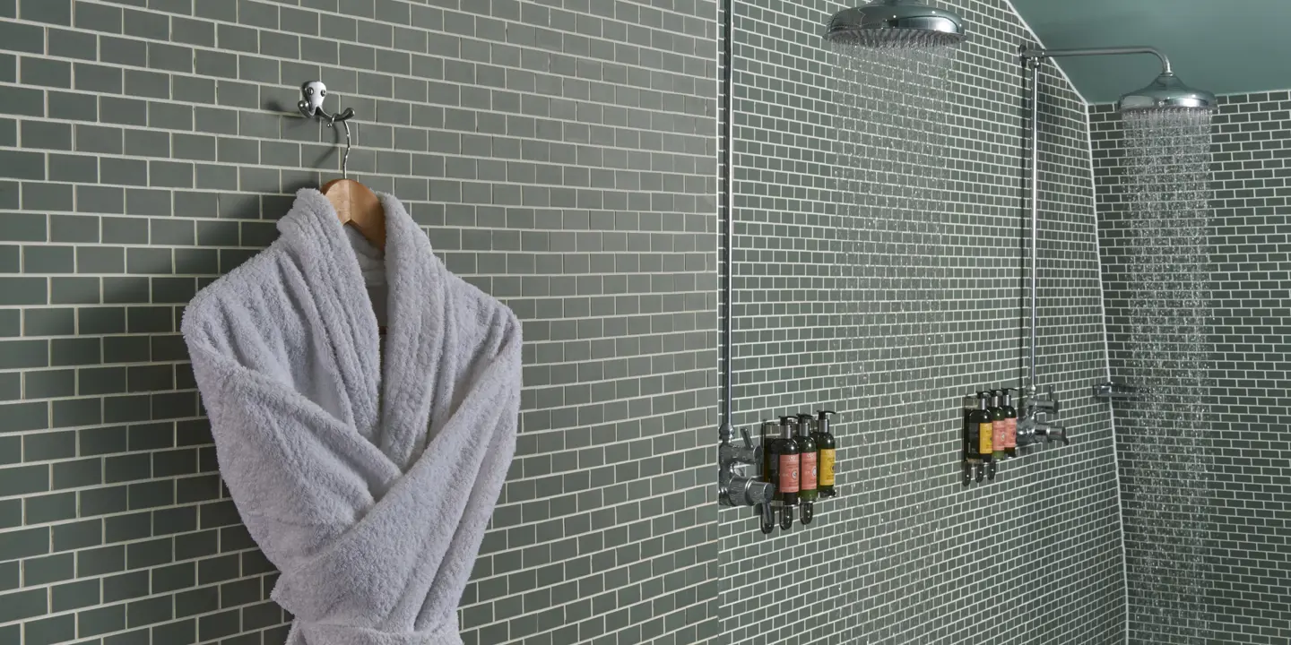 Bathroom wall with a hanging grey dressing gown.