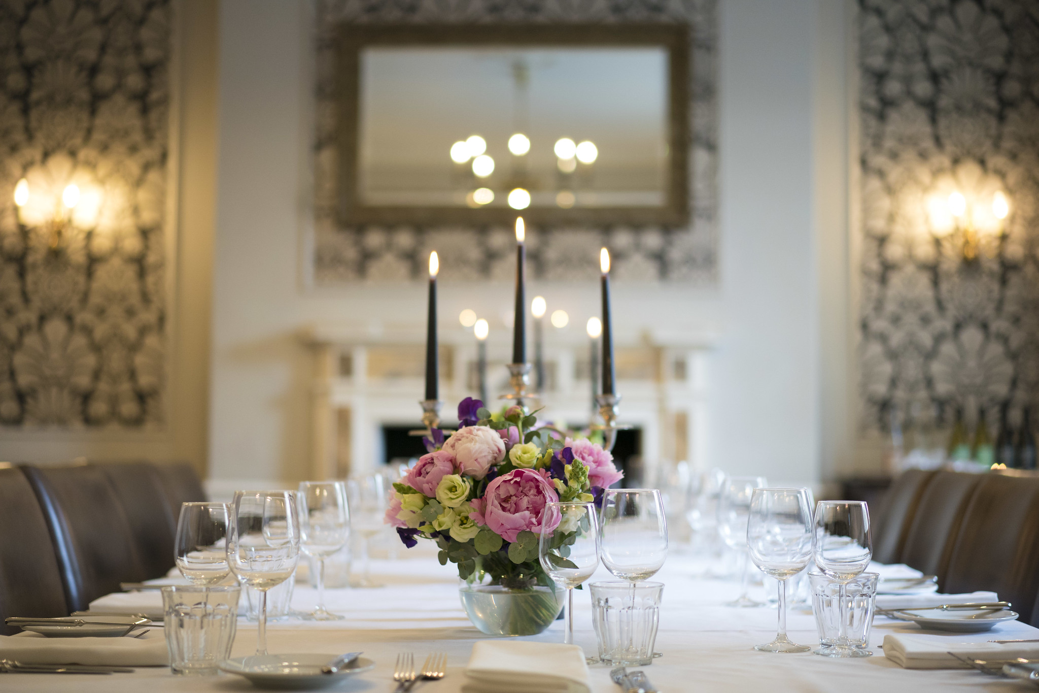 Table elegantly set for a formal dinner, adorned with candles and flowers.