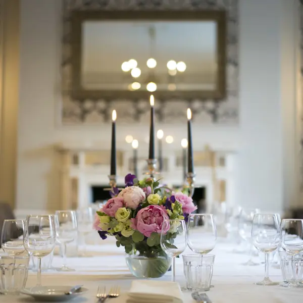 Table elegantly set for a formal dinner, adorned with candles and flowers.