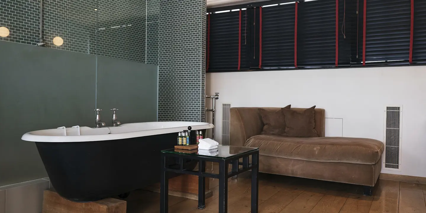 A bathroom featuring a bathtub, chair, and window.