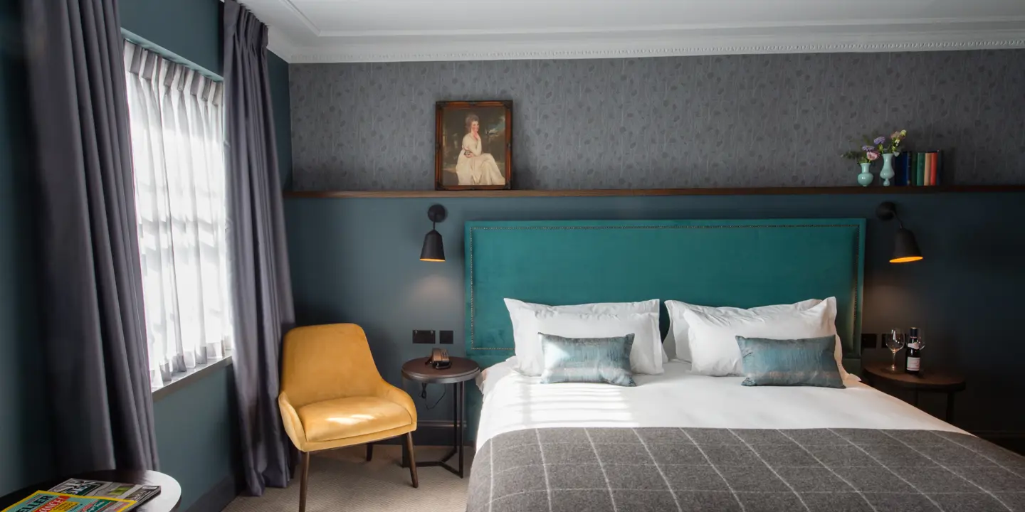 Bedroom featuring a blue headboard and a yellow chair.