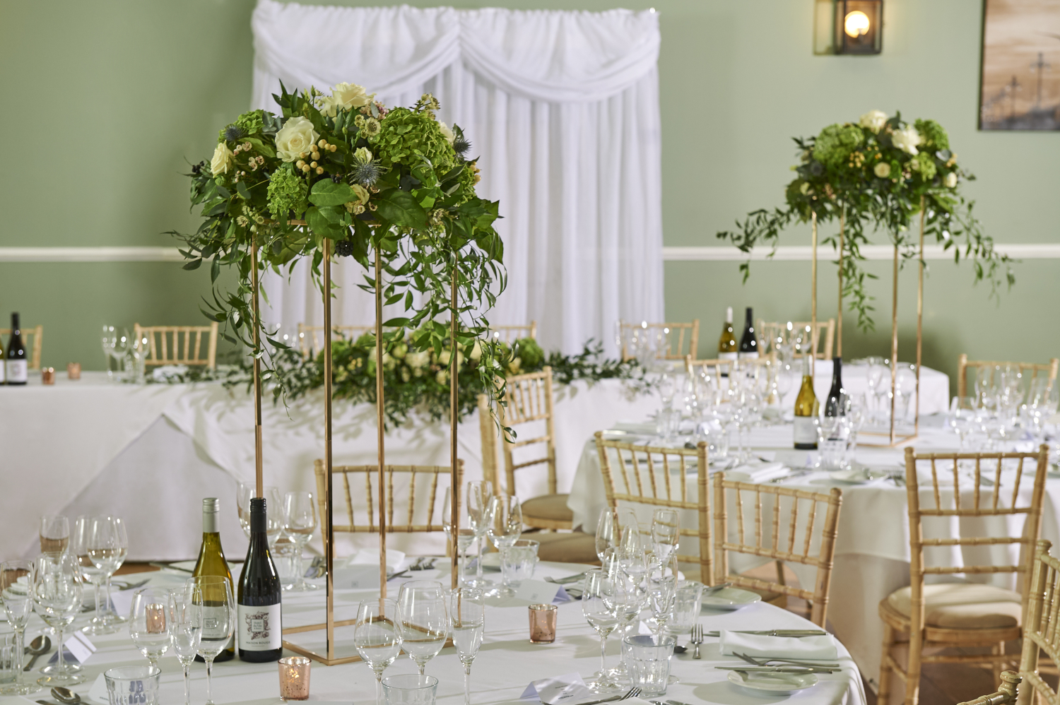 tables set for wedding breakfast with bottles of wine and beautiful flower arrangements