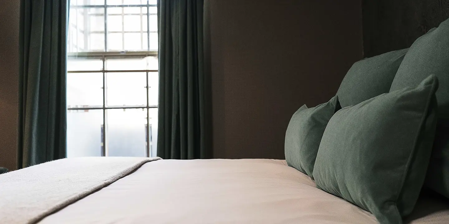 A bed adorned with green pillows and a pristine white blanket.