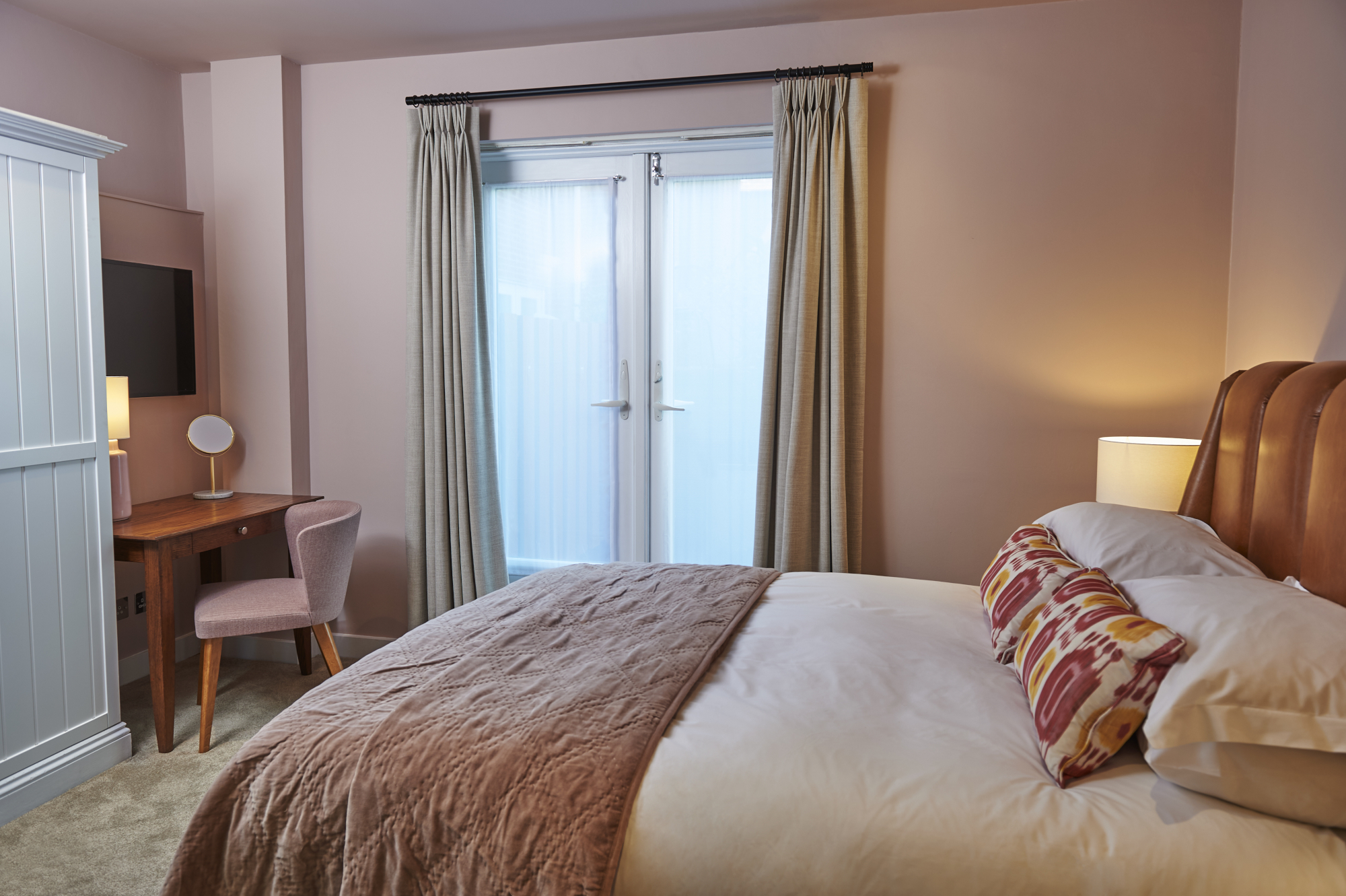 Bedroom featuring a comfortable bed, desk, and opening glass door.