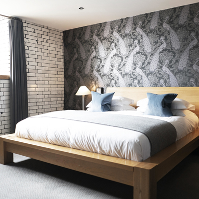 Spacious bedroom featuring a king-sized bed and an exposed brick wall.