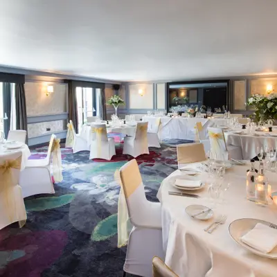 An elegantly decorated banquet room featuring pristine white tables and chairs.