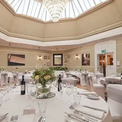 An elegantly decorated banquet room featuring pristine white tables and chairs.