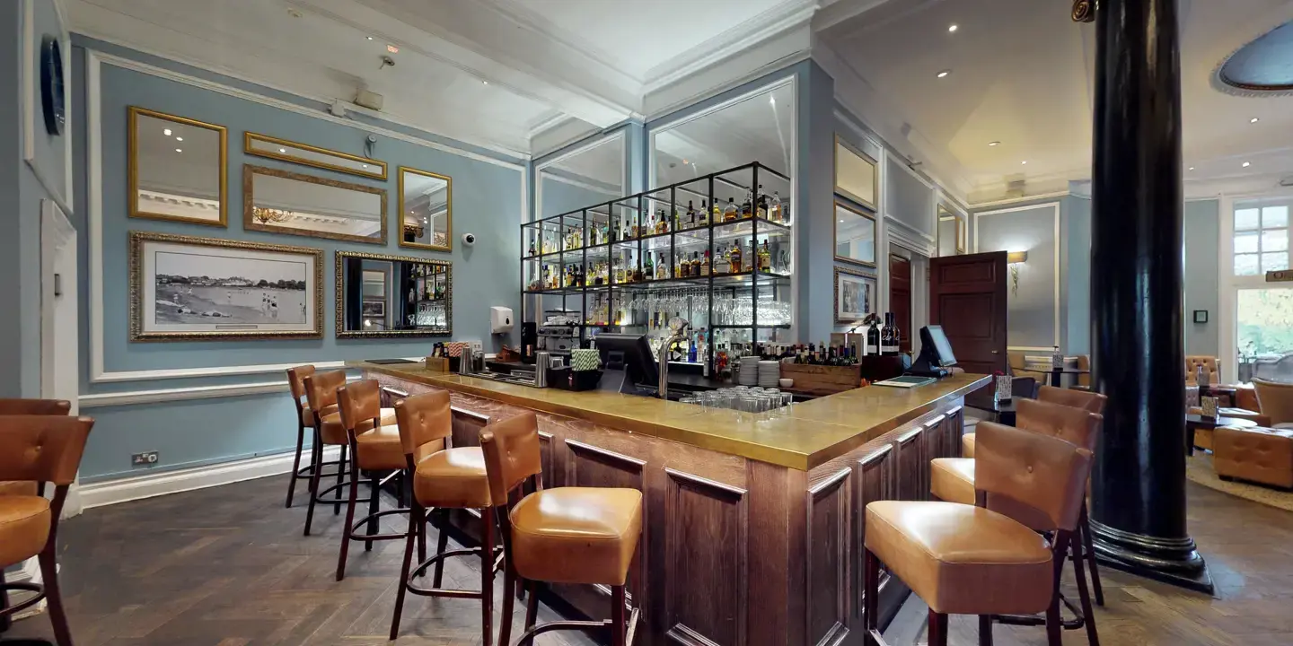 A bar with numerous leather bar stools surrounding it.