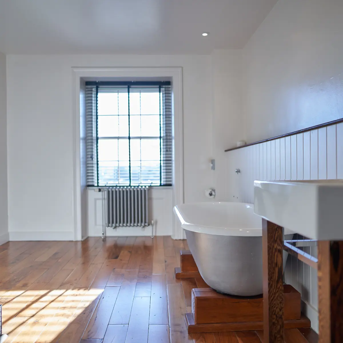 A bathroom featuring a bathtub, sink, and window.