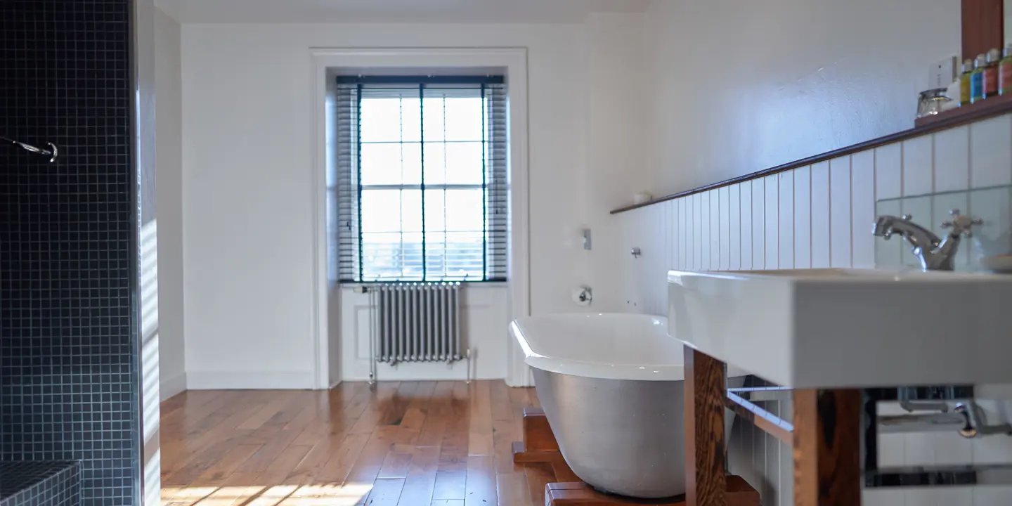 A bathroom featuring a bathtub, sink, and window.