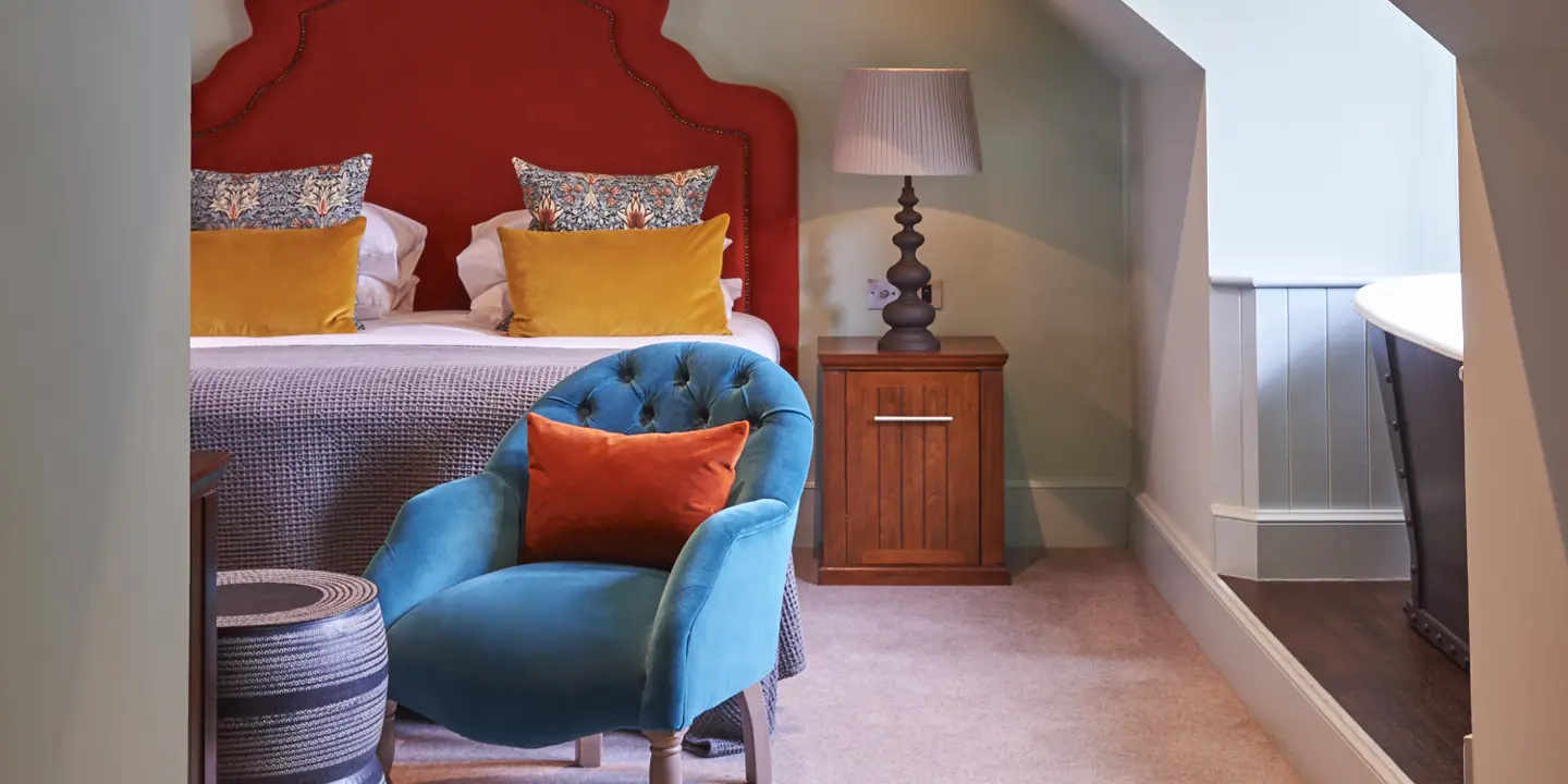 A suite decorated in bright colours. There is a bed and a bath in view