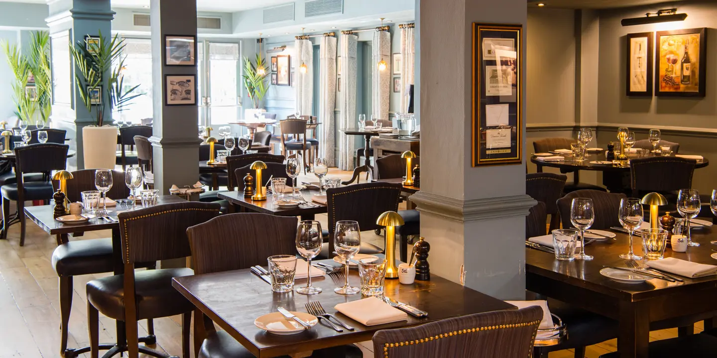 A restaurant featuring tables, chairs, and wine glasses.